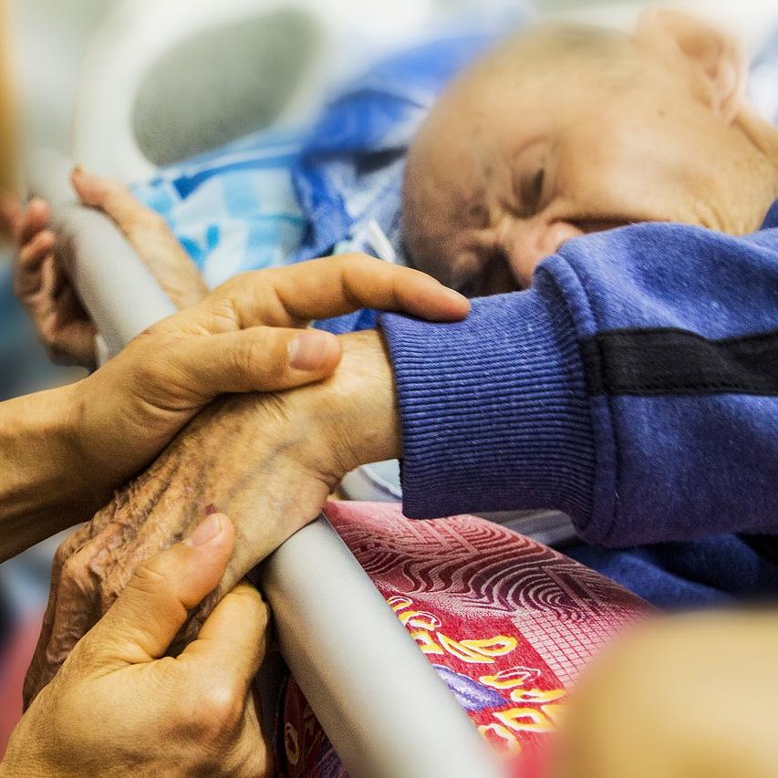 Držanje moškega, ki leži na bolniški postelji, za roke