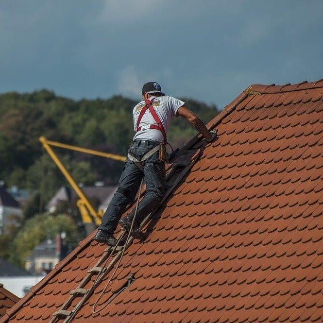Moški opravlja krovska dela na strehi.