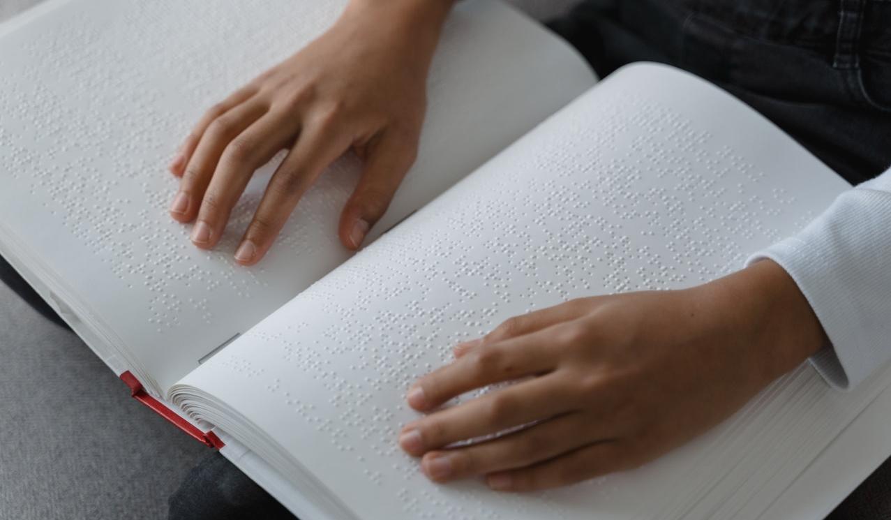 Knjiga v Braillovi pisavi in roke.