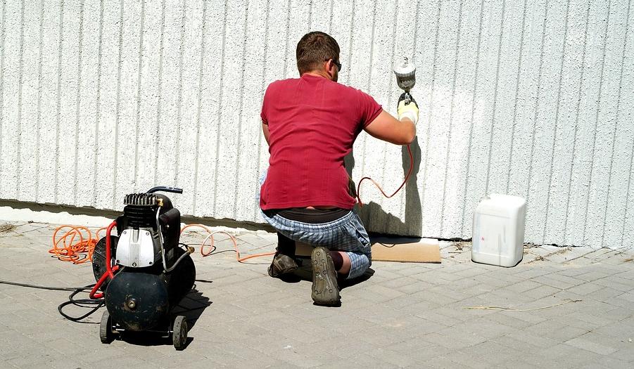 Pleskanje zidu s pomočjo kompresorja, ki prši barvo.